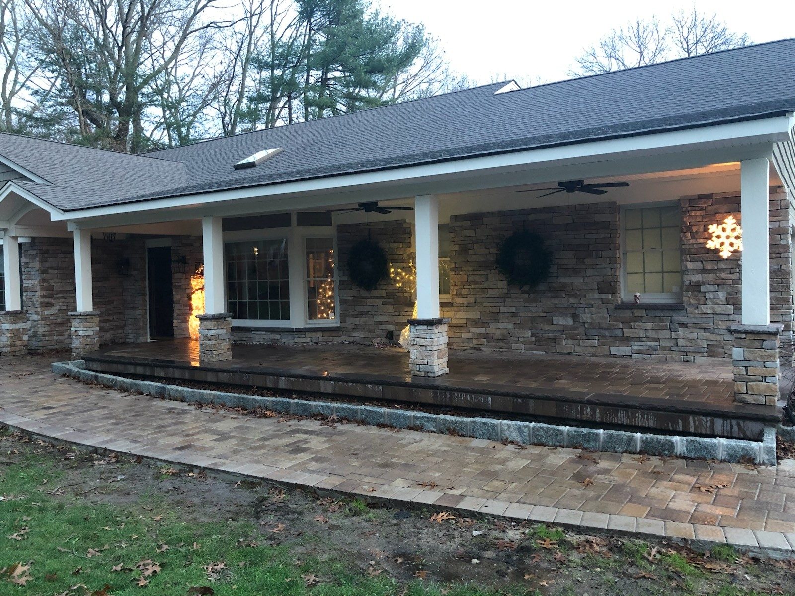 Roof on a Long Island ranch home with stone porch columns and paver patio